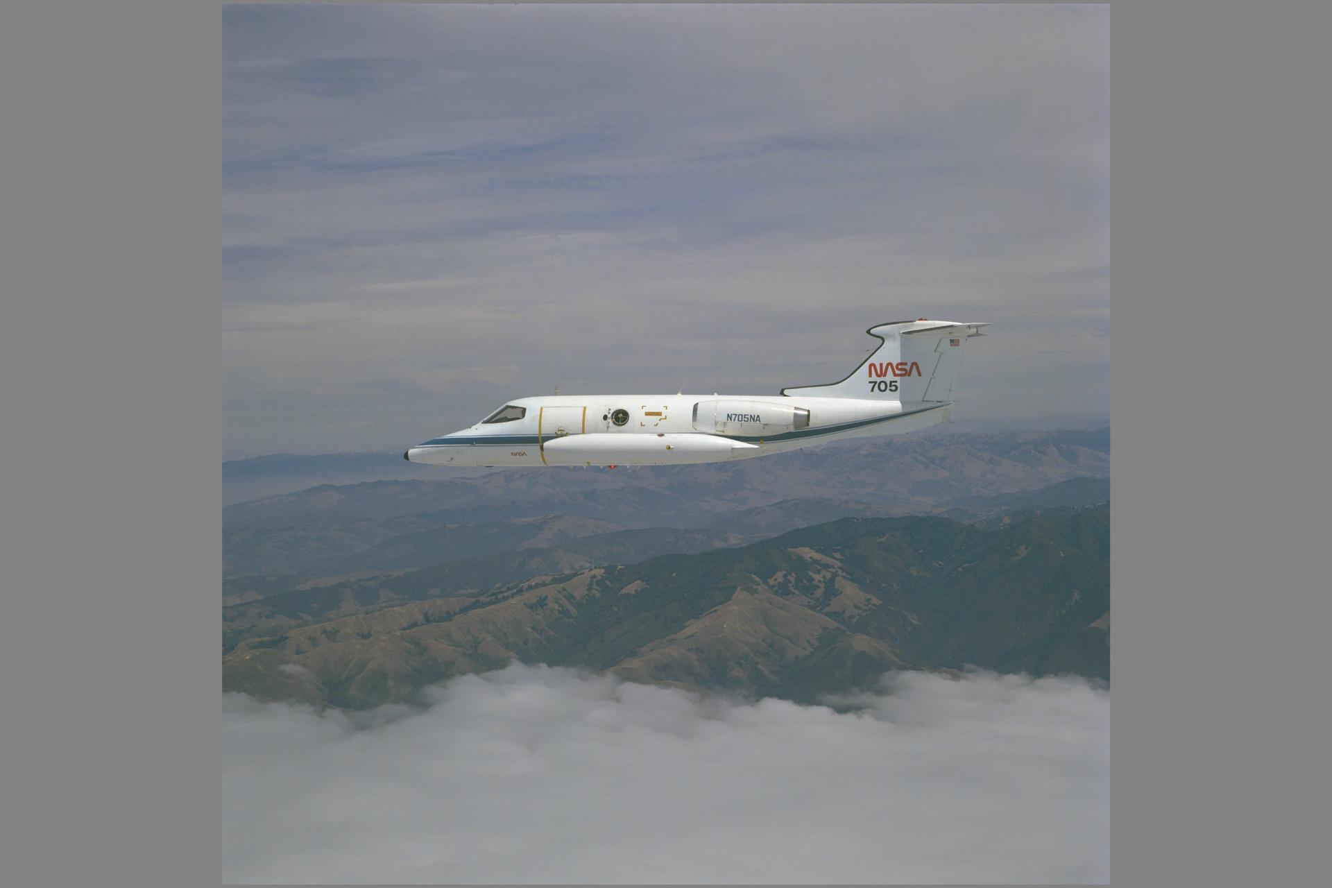 NASA’s Learjet 24B in profile above California mountains and a layer of clouds in 1982